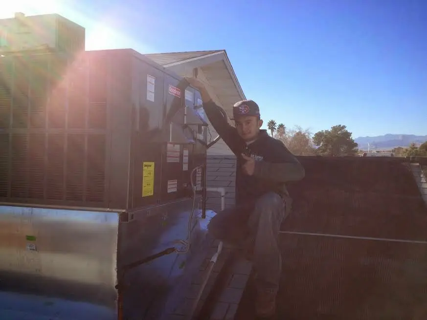 HVAC technician performing AC Tune-Up on a rooftop unit in Anamosa